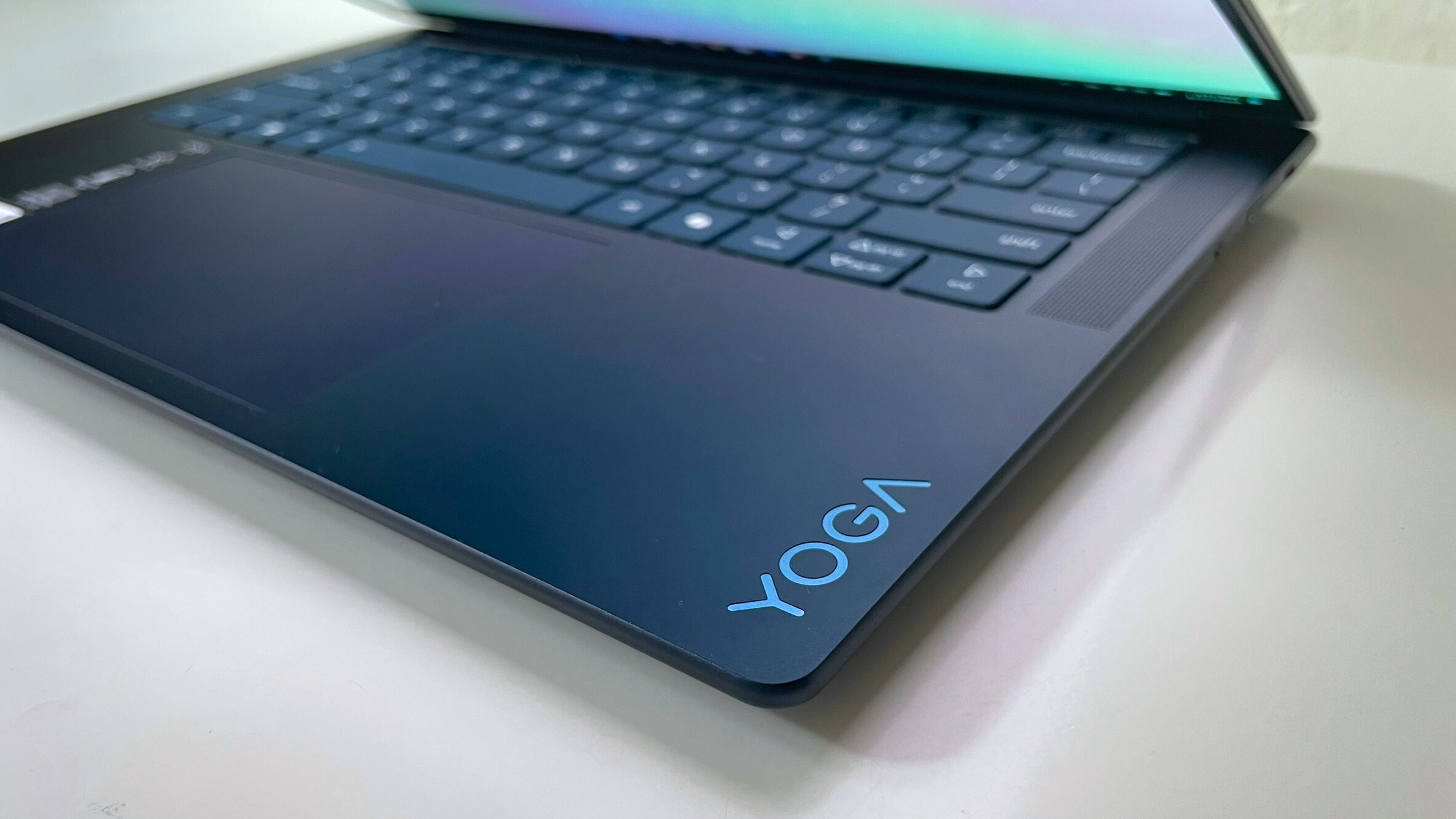 A close up of a laptop logo in the bottom right hand corner of a laptop's keyboard and trackpad area.