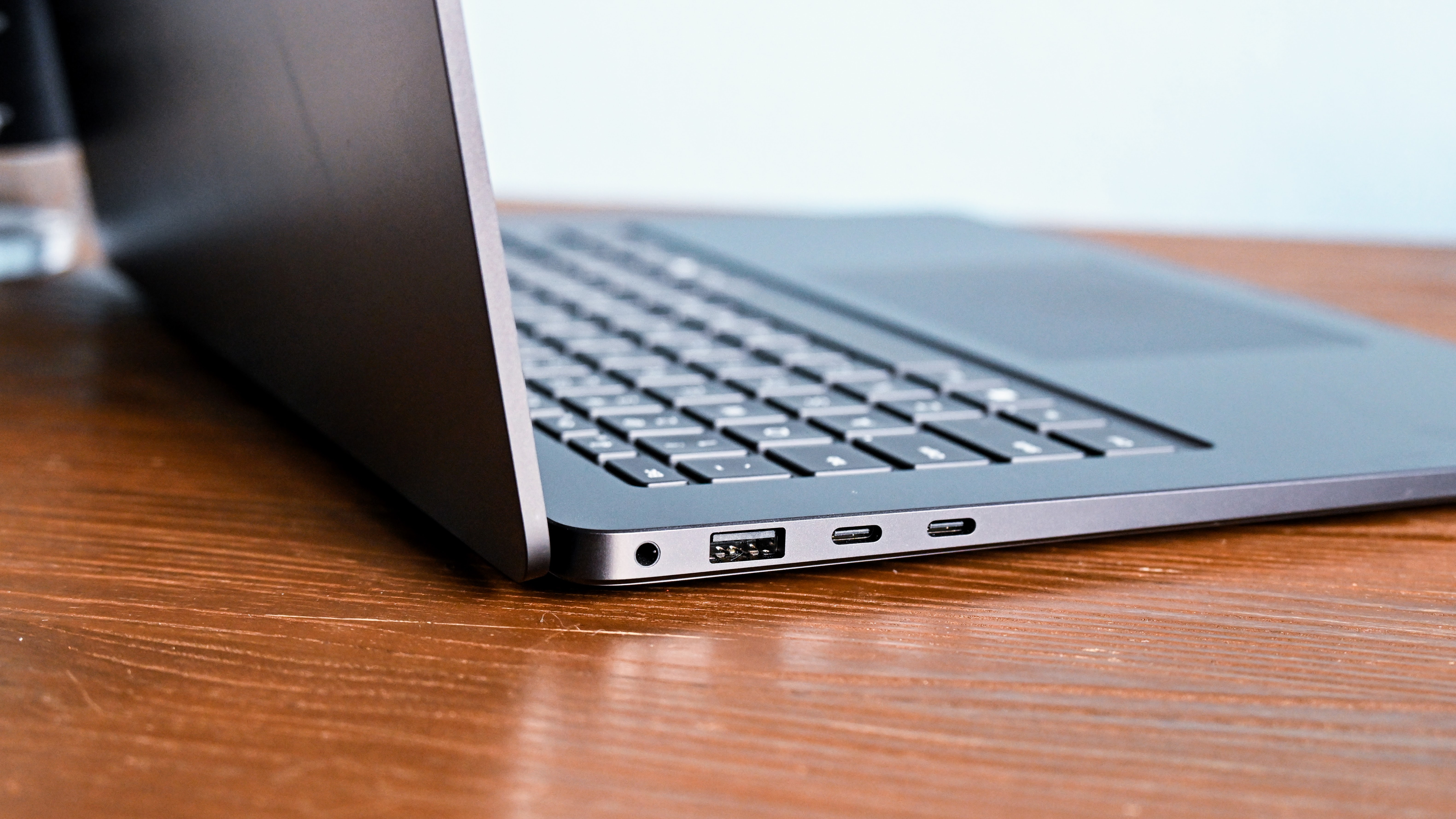 Microsoft Surface Laptop 7 15 on wooden desk, close up showing left hand side ports, including dual USB-C, USB-A and 3.5mm audio.