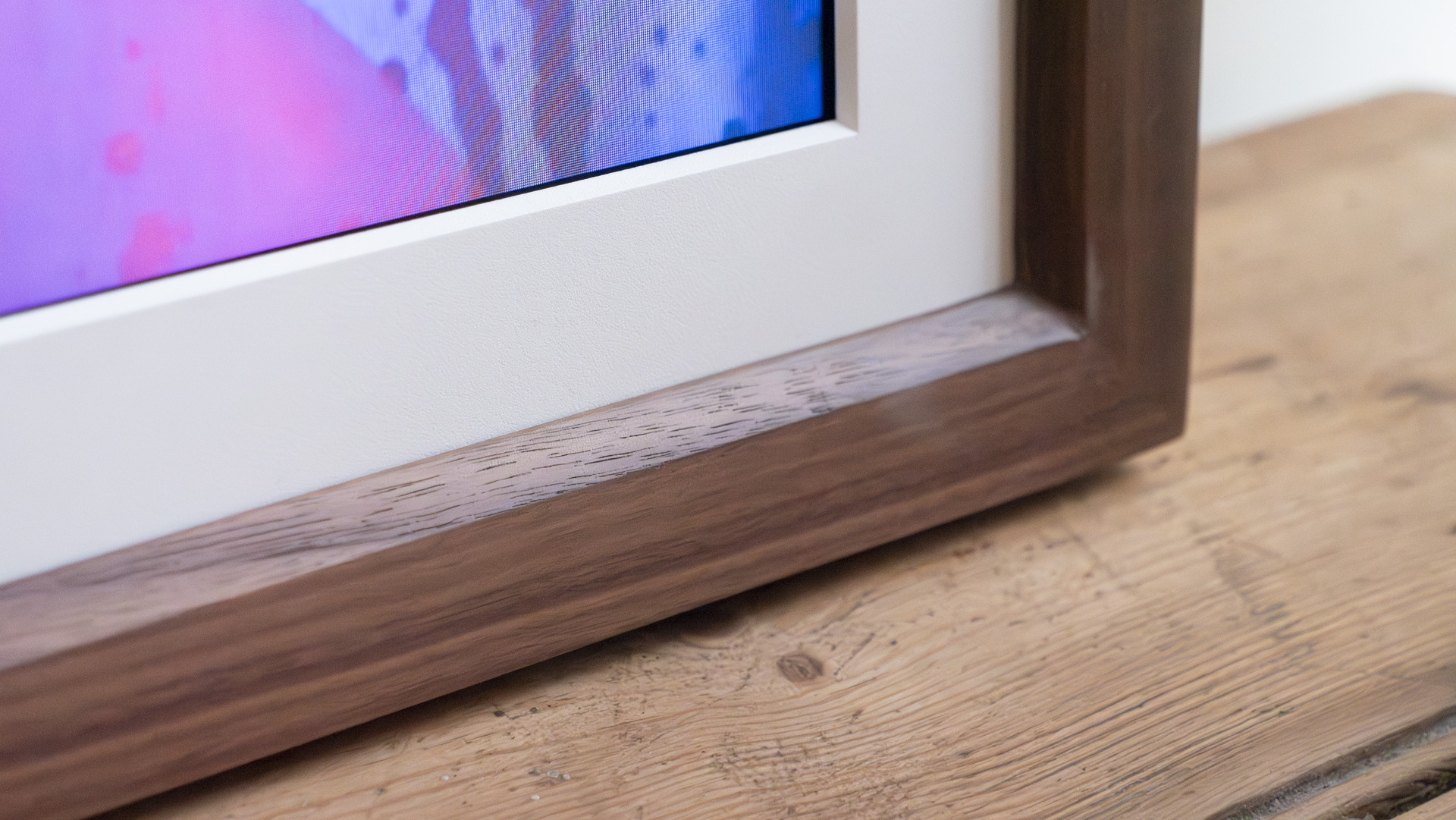 Closeup of the frame corner of the Vieunite Textura digital canvas on a wooden table by a window
