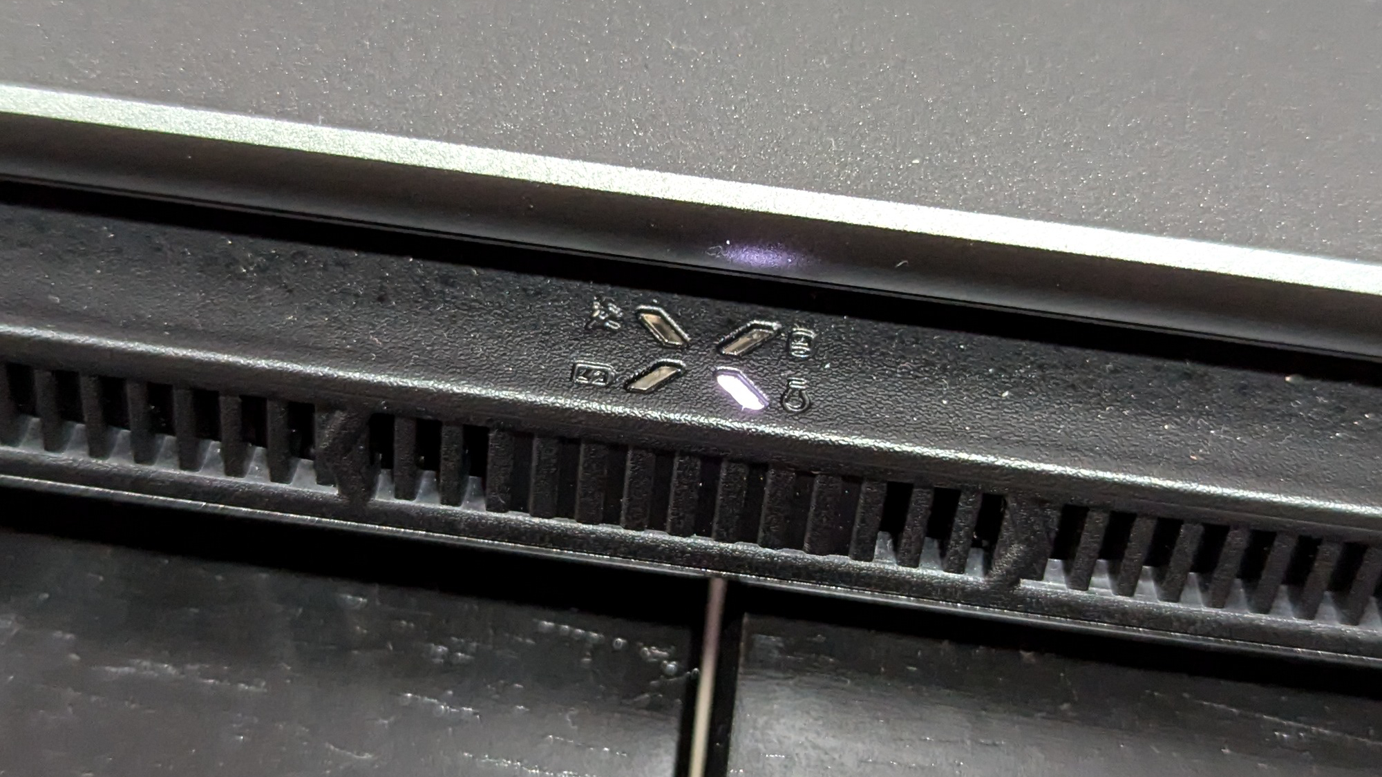 A close up of a small logo near the exhaust vents on a laptop.