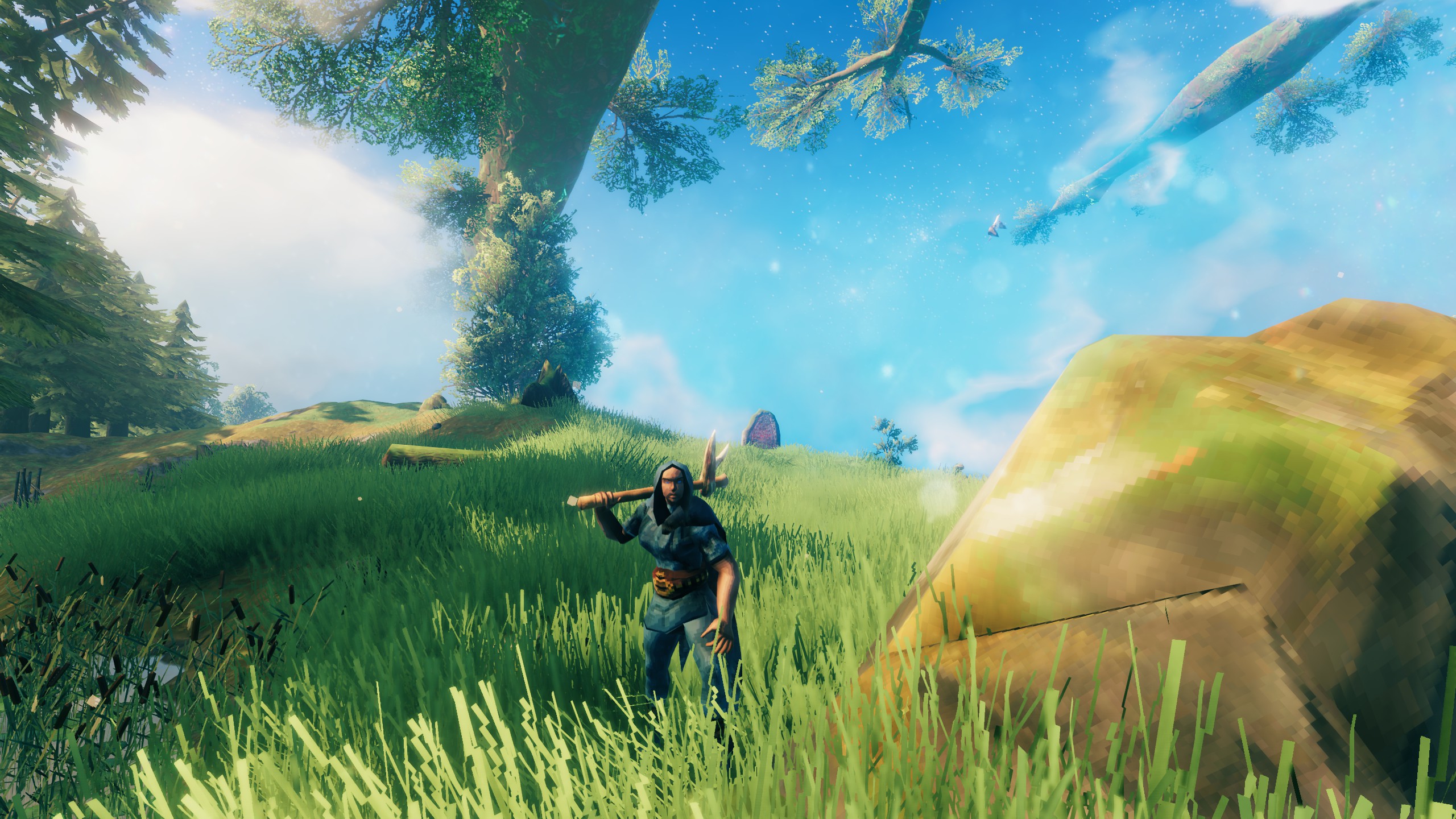 Valheim - a player stands in a grassy field hefting a pickaxe