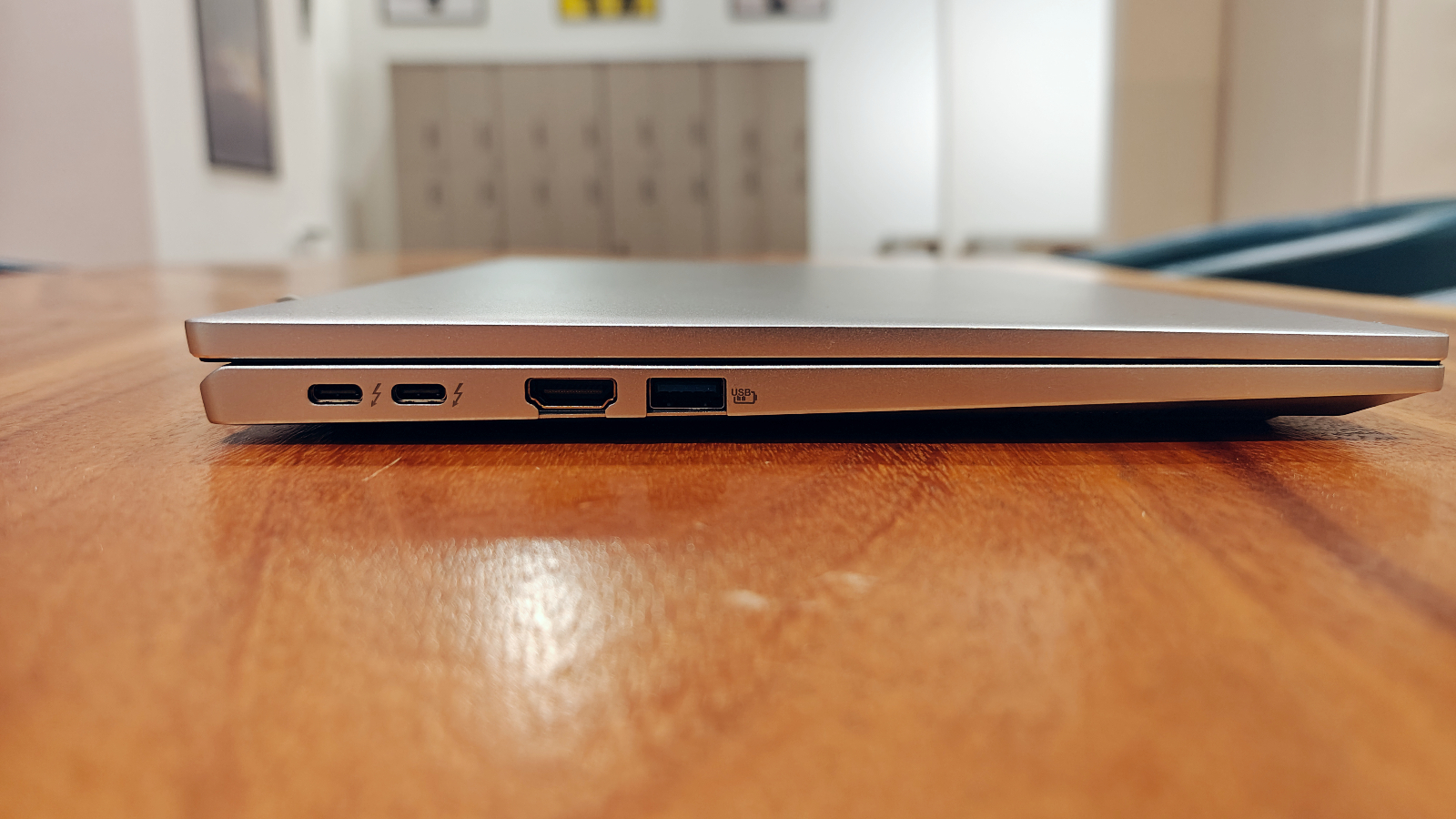 Sideview photo of the Acer Swift Go 14 closed on a wooden table showing thinness and the side ports