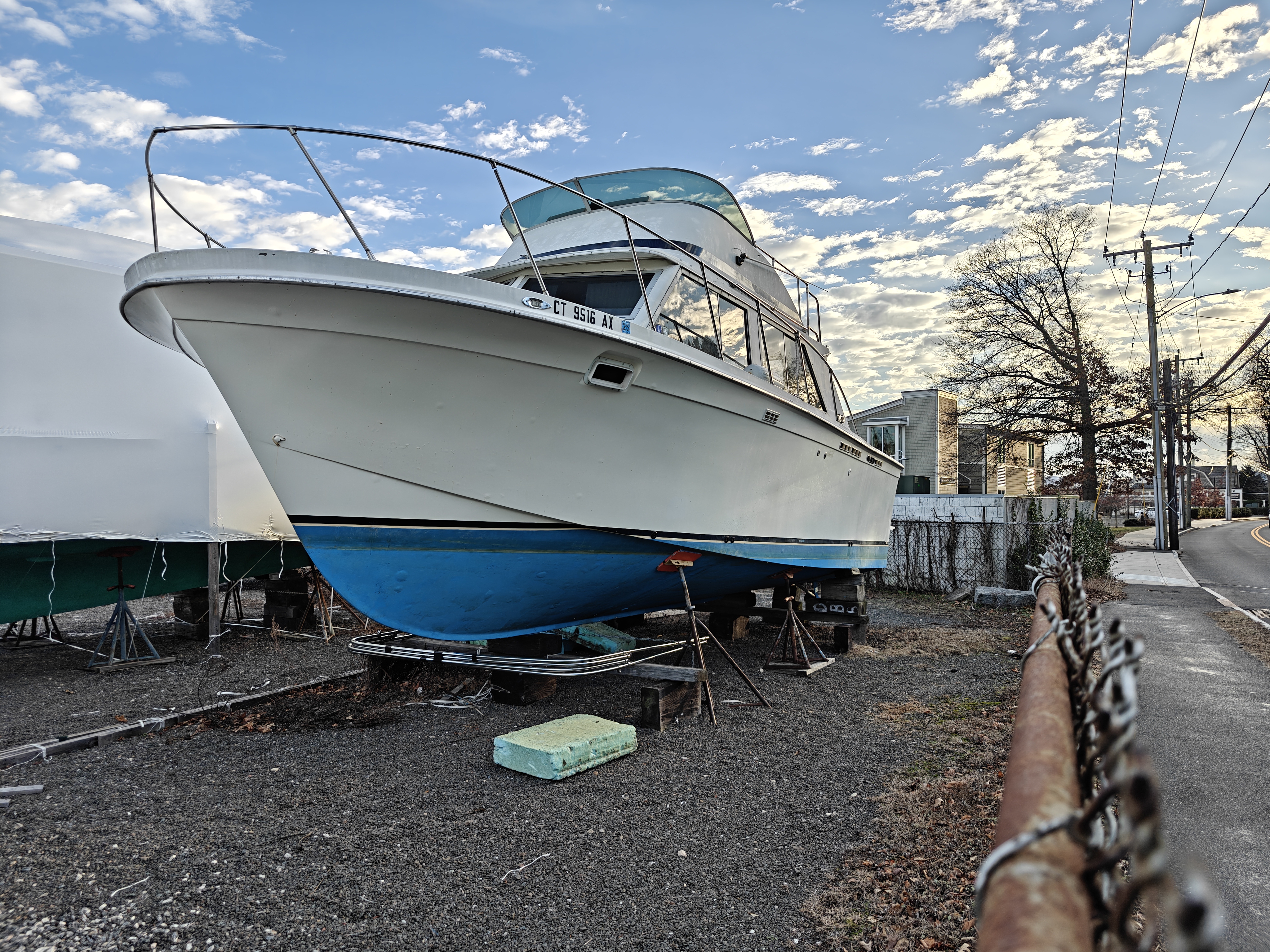 A small fishing boat on land with a street behind
