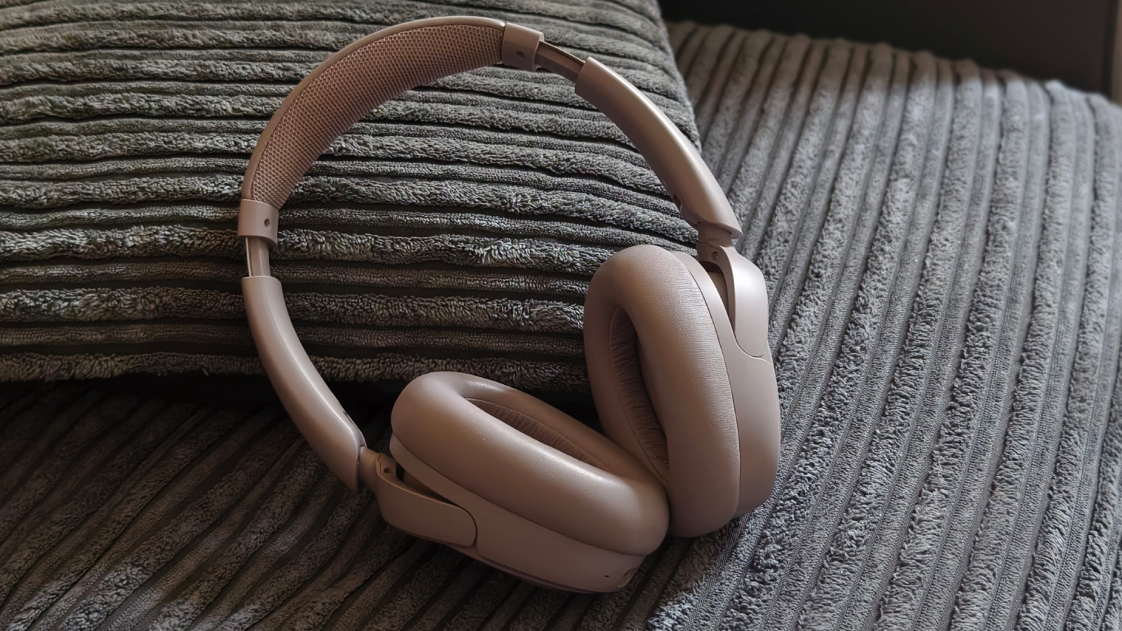 The JLab JBuds Lux ANC laying on a textured surface