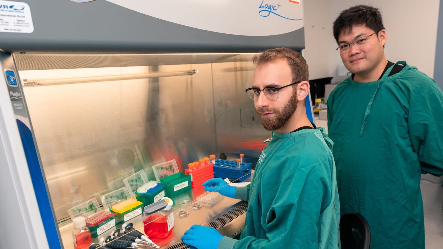 Brett Kagan (center) and Cortical Labs CEO Hon Weng Chong (right) next to a DishBrain system in the laboratory.