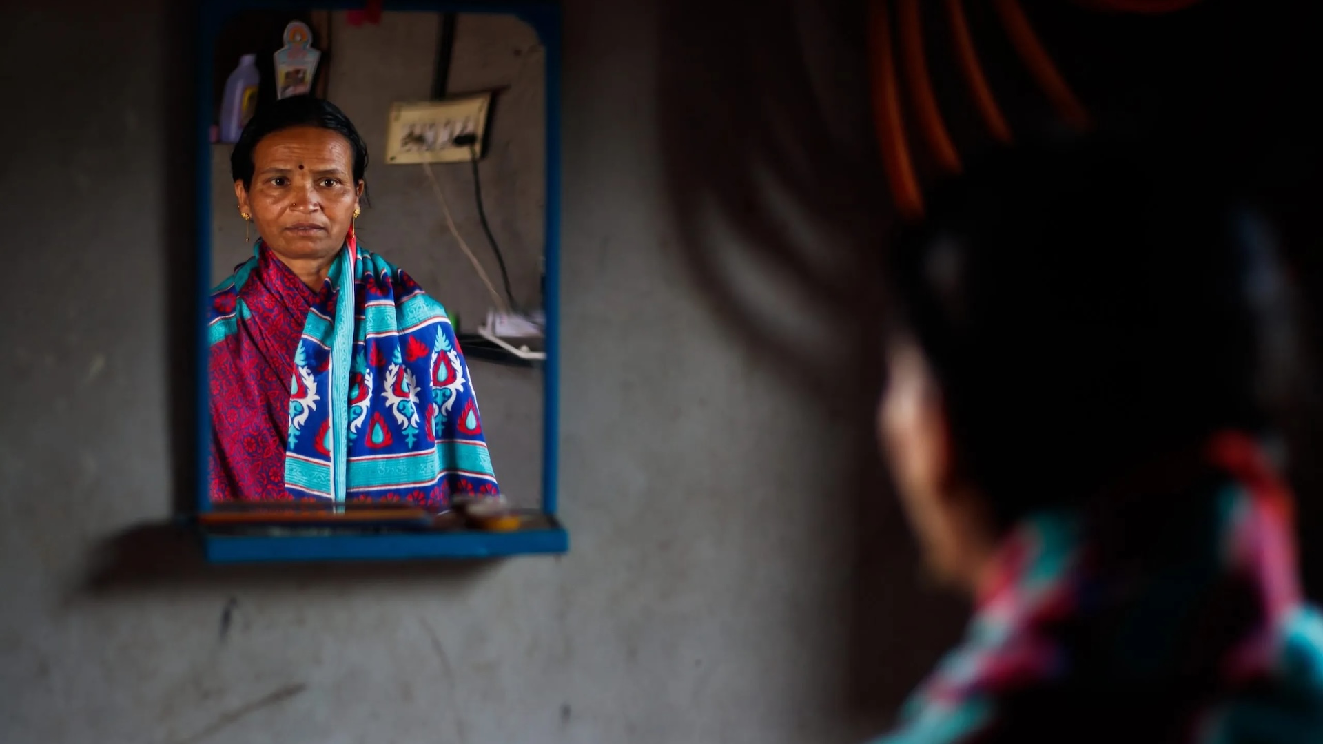 A photo of an Indian woman looking in the mirror