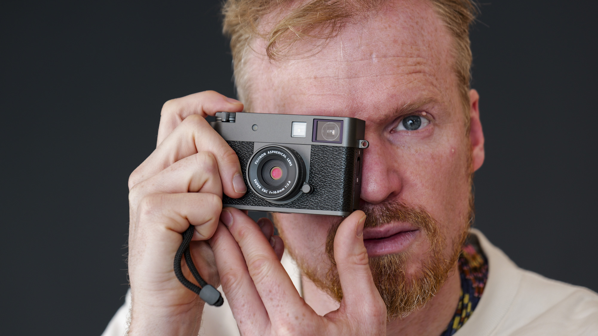 Fujifilm X half compact camera being held up to person's eye