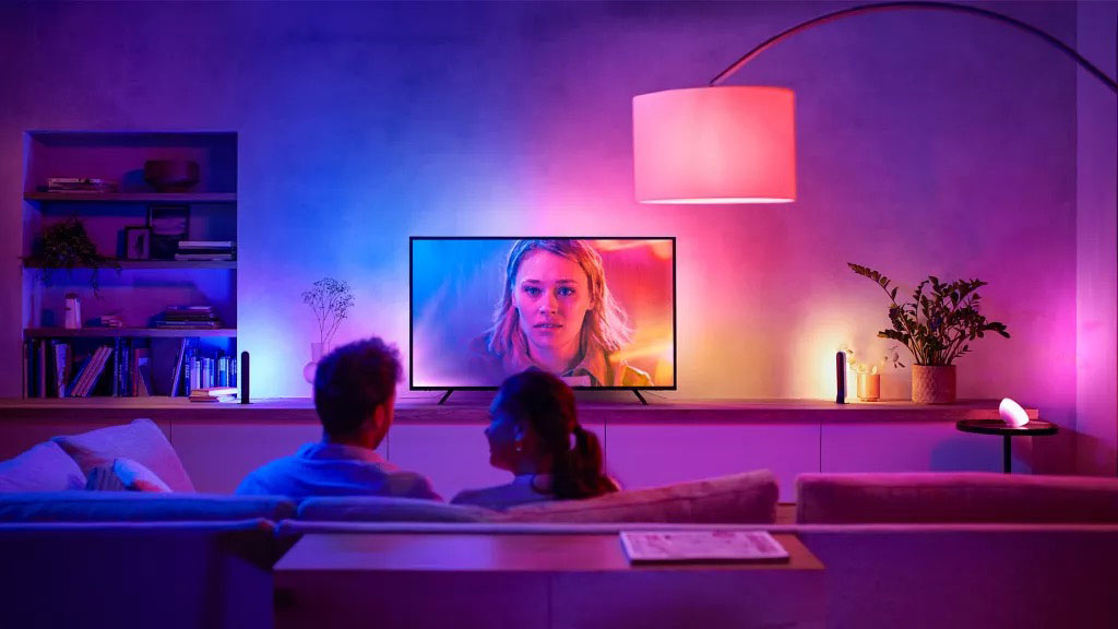 Par i sofaen omgitt av hyggelig og fargeglad belysning